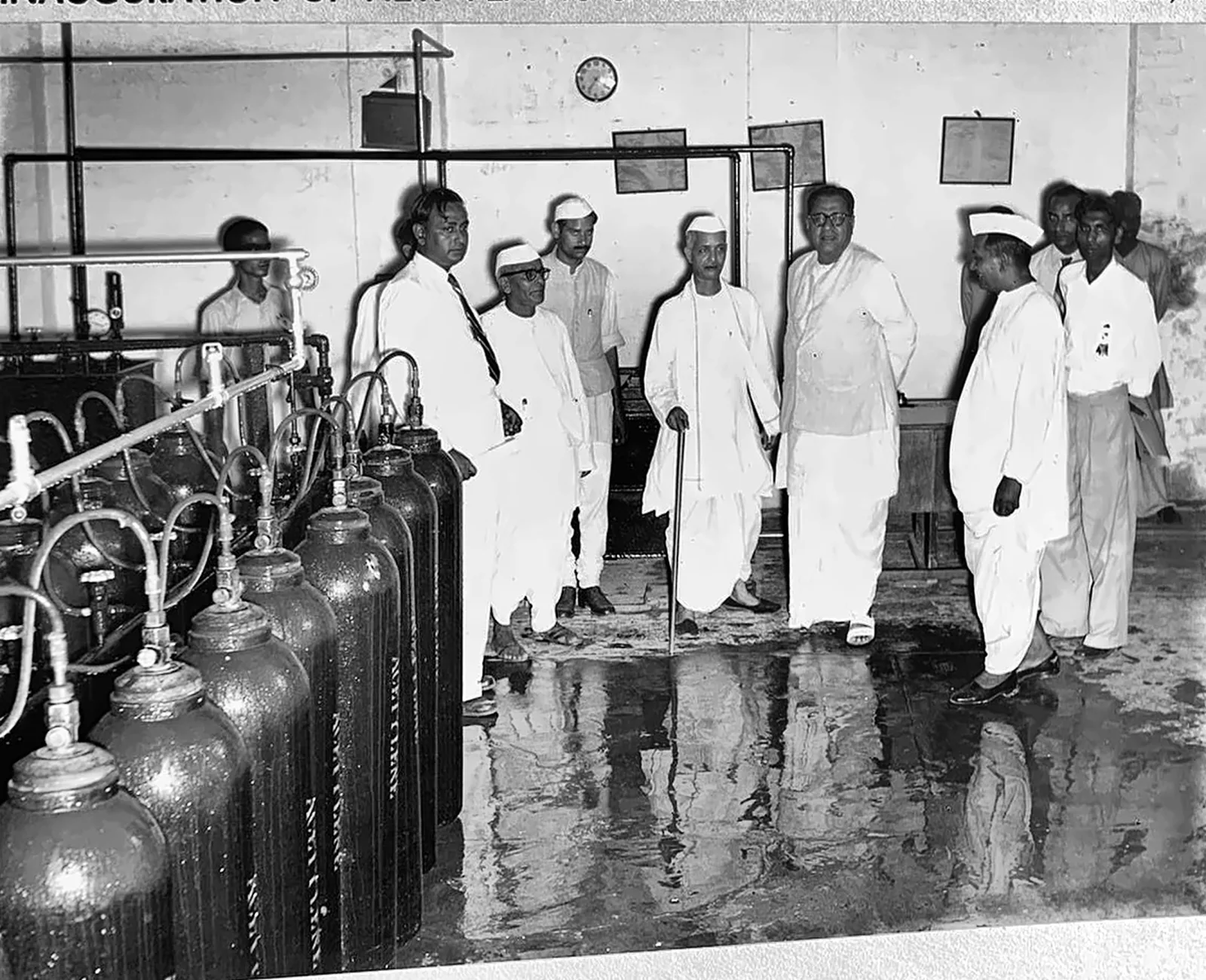 Dignitaries beside an acetylene cylinder filling manifold in 1956, cylinders stencilled ACETYLENE